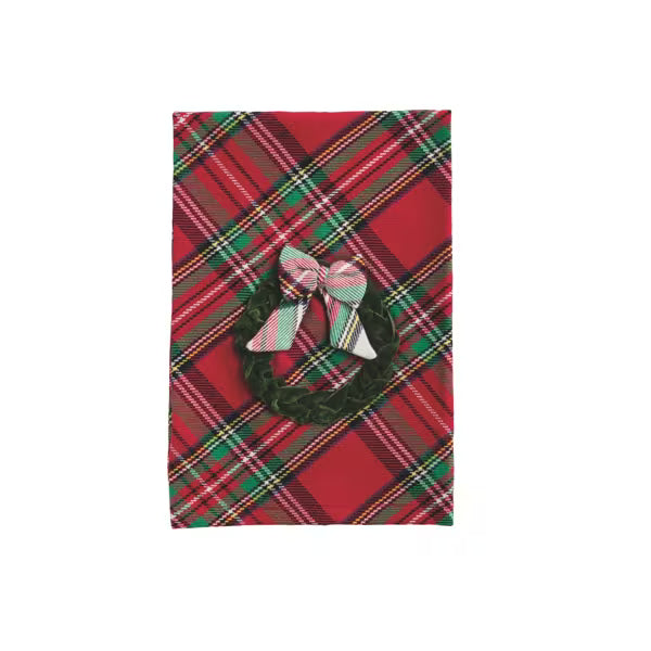 A rectangular red tartan plaid fabric item, likely a napkin or small table linen, featuring a dark green wreath and pink bow motif in the center.