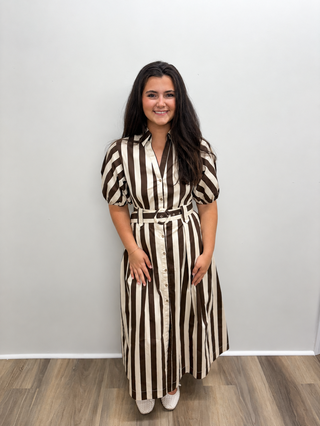 Women’s brown and cream vertically striped midi shirt dress featuring a collared neckline, button-front closure, short puff sleeves, side pockets, and a coordinating belted waist.