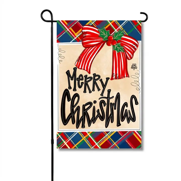 Christmas garden flag featuring “Merry Christmas” in bold black lettering, accented with a red-and-white striped bow, holly leaves and berries, and a festive red, green, and navy plaid border.