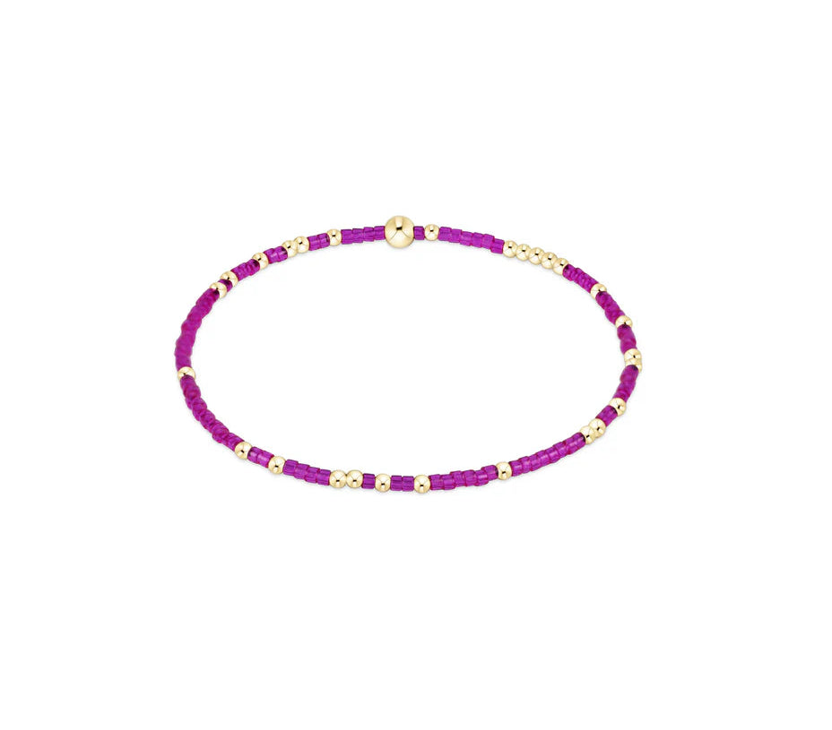 Purple beaded bracelet with gold accents on a white background