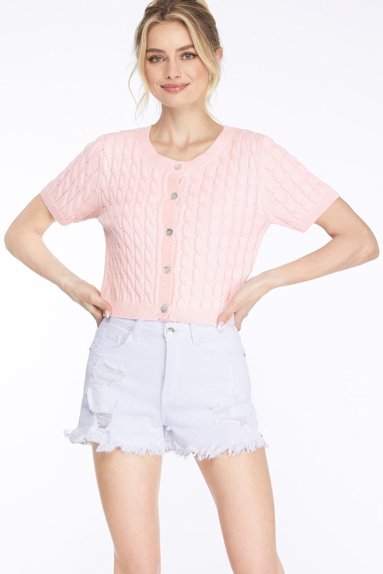 A light pink short sleeve design, button down closure, and cable knit detailing sweater