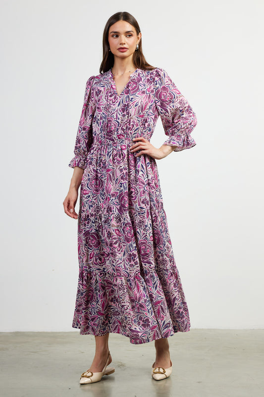 A long sleeved maxi dress features a vibrant print with different shades of purple. 