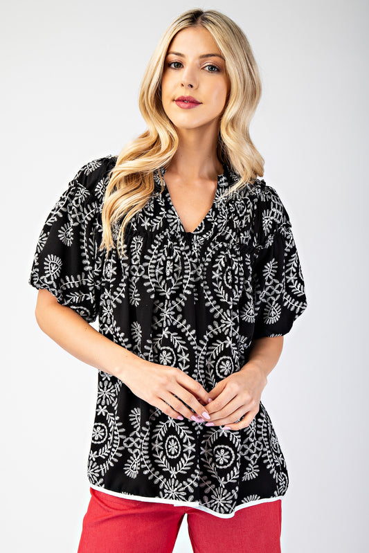 A black with a white pattern top, being a V-neck with short sleeves. 