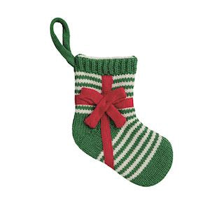 A small knitted Christmas stocking ornament in green and white stripes with a red bow, shown on a plain white background.
