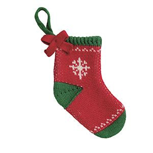 A small knitted Christmas stocking ornament in red and green with a white snowflake motif, featuring a hanging loop at the top.