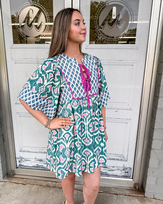 Onyx dress with a tie slit neckline and wide sleeves in a emerald and pink design.