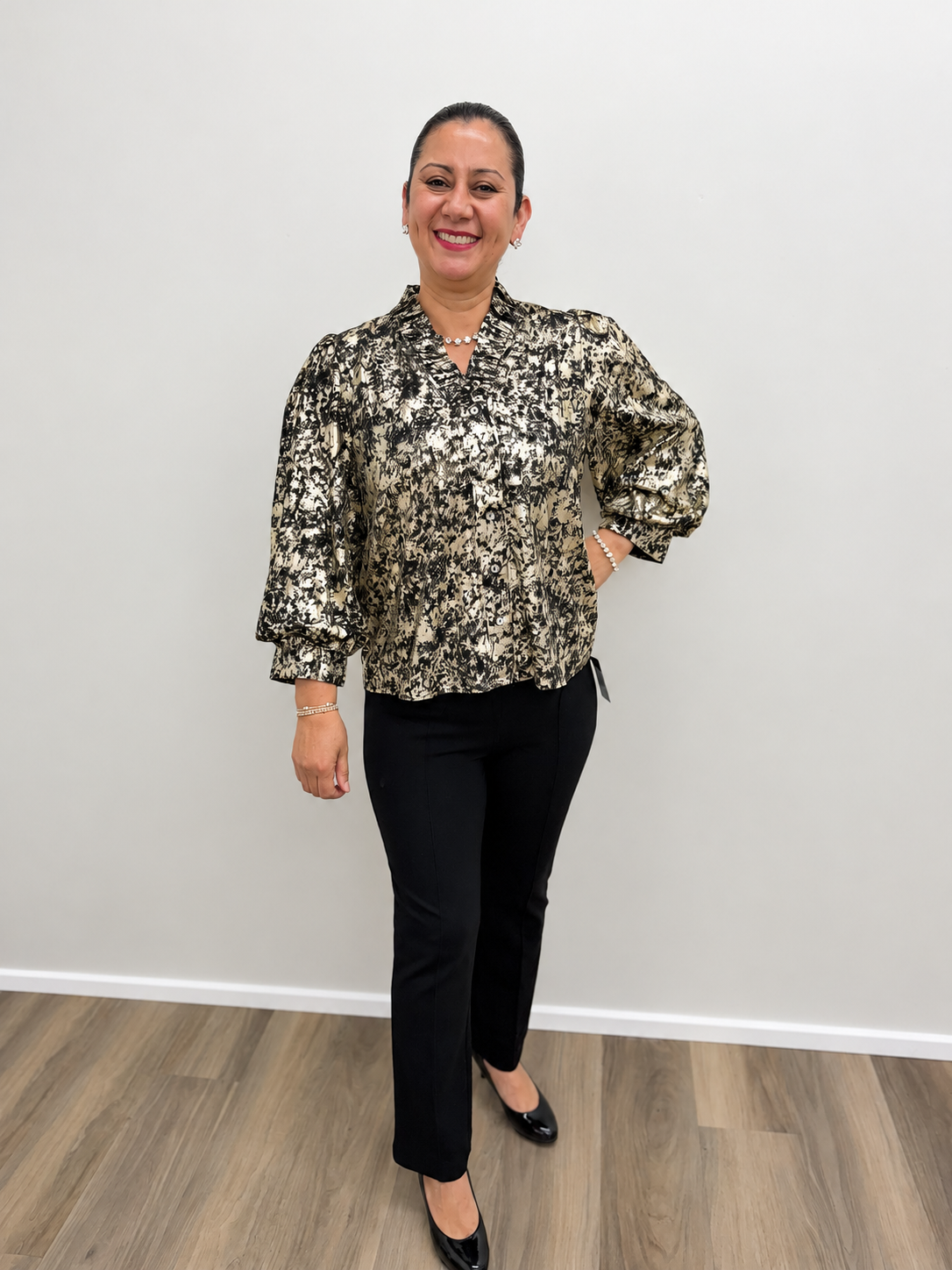 Women’s black and gold metallic print blouse featuring a button-front design, V-neckline, and long puff sleeves with cuffed wrists.