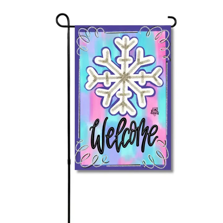 A colorful winter garden flag featuring a large white snowflake outlined in gold against a vibrant pastel background of blue, purple, and pink. The elegant black script lettering reads “Welcome,” complemented by delicate decorative swirls around the border. Perfect for adding a cheerful, whimsical touch to your front yard, garden, or porch throughout the winter season.