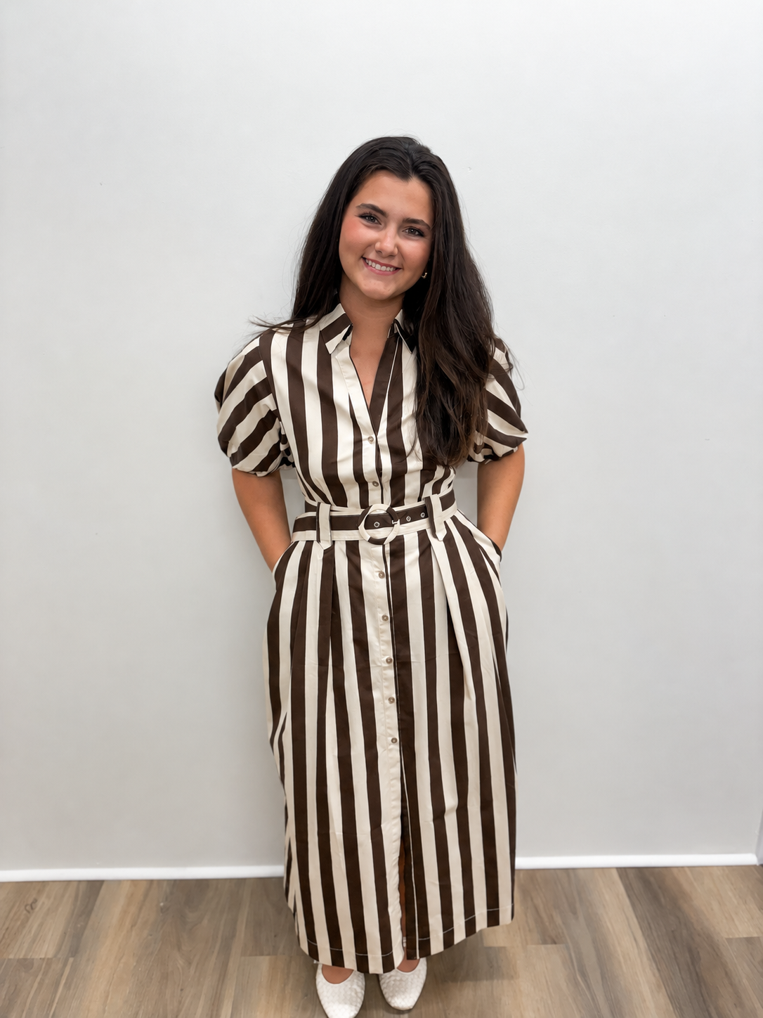 Women’s brown and cream vertically striped midi shirt dress featuring a collared neckline, button-front closure, short puff sleeves, side pockets, and a coordinating belted waist.