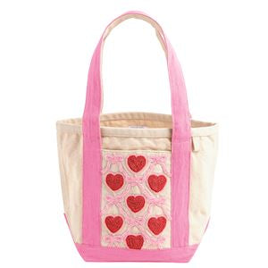 A small canvas tote bag with pink handles and trim, featuring a front pocket decorated with red hearts and pink bows on a white background.
