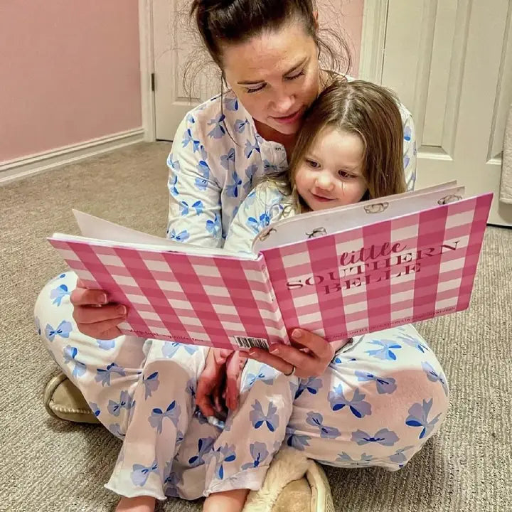 Mom and daughter in bow pajama's reading the Little Southern Belle Book.