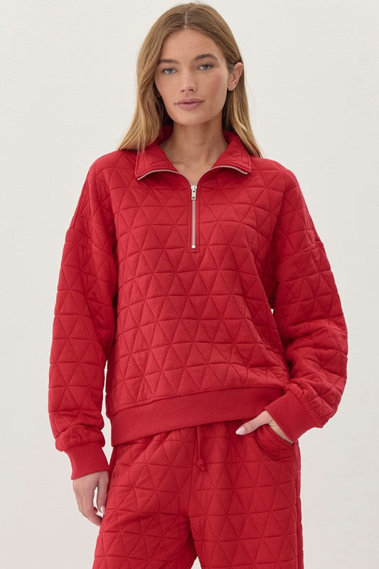 Red quilted sweater with geometric triangle stitching pattern. Has a collar and half-zip closure in the front. Elastic cuffs at the wrists and bottom of the sweater