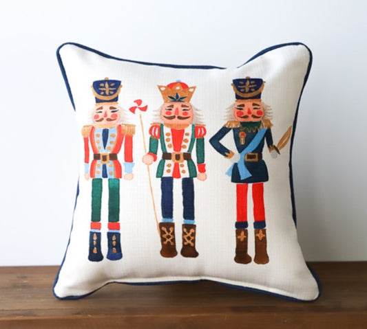 A cream pillow with three different style nutcrackers. 