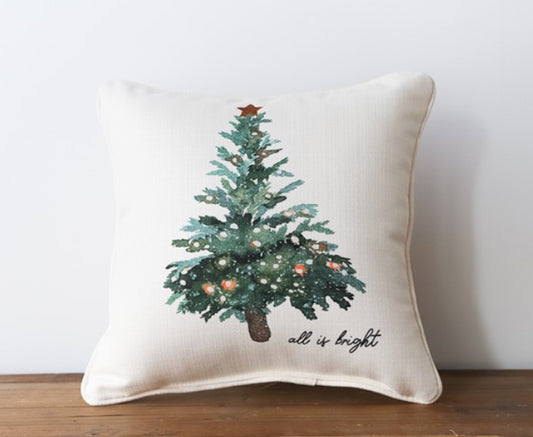 A cream pillow with a Christmas tree in the center with the words "all is bright" in cursive in to bottom right corner.