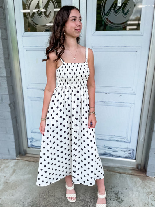 A black and white polka dot satin midi dress with pockets.