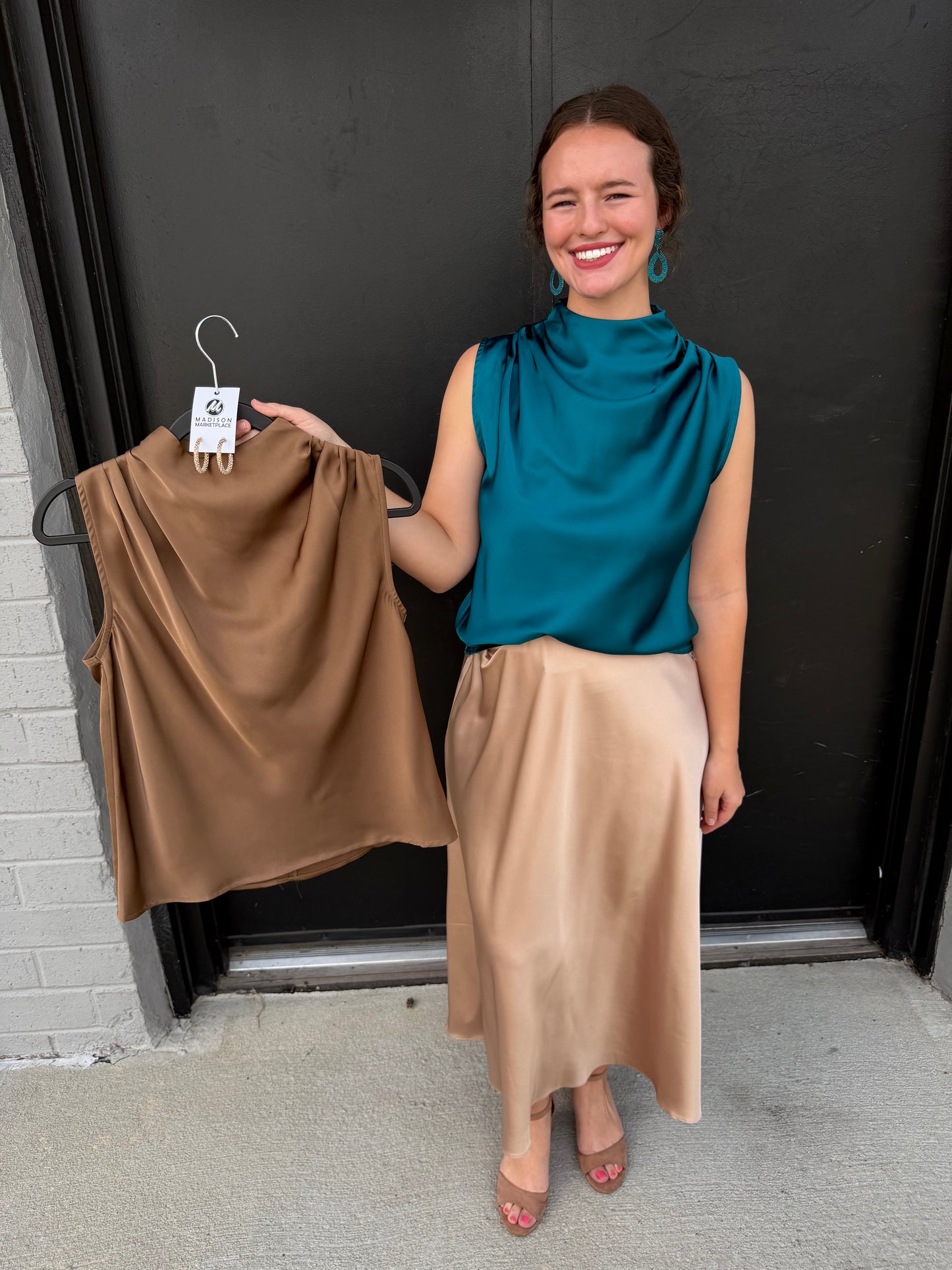 This teal satin sleeveless top has an elegant, polished look with beautiful draping.

Color: Rich teal/blue-green
Neckline: High cowl-style neckline with soft gathered folds
Sleeves: Sleeveless, with clean shoulder lines
Fit: Relaxed, fluid silhouette that drapes naturally over the body
Fabric: Smooth, lustrous satin-like material with a subtle sheen
Hem: Straight, slightly relaxed hem that sits around the hip