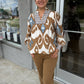 This bohemian-inspired printed blouse combines an earthy palette with beautiful statement details:

Color: Warm camel brown, ivory, and soft blue
Print: Bold, oversized geometric/ikat-inspired pattern throughout
Neckline: Split neckline with a structured, embroidered-looking bib panel in blue, ivory, and brown
Sleeves: Long sleeves with a relaxed, slightly voluminous shape and gathered cuffs
Cuffs: Coordinating patterned cuffs with a gathered finish
Fit: Relaxed, easy silhouette with a softly flowing body
H