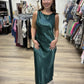 This is a rich emerald green satin maxi dress with an elegant, fluid silhouette. The lustrous fabric has a beautiful sheen that catches the light, giving the dress a sophisticated, dressy finish.

It features a sleeveless design with a softly rounded bateau neckline in front and a striking low scoop back with a draped cowl detail. The dress skims the figure before falling into a relaxed, flowing ankle-to-maxi length hem. Minimalist yet glamorous, it’s a beautiful option for weddings, formal events, holiday 