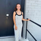 Woman in a black and white striped dress standing outside a building.