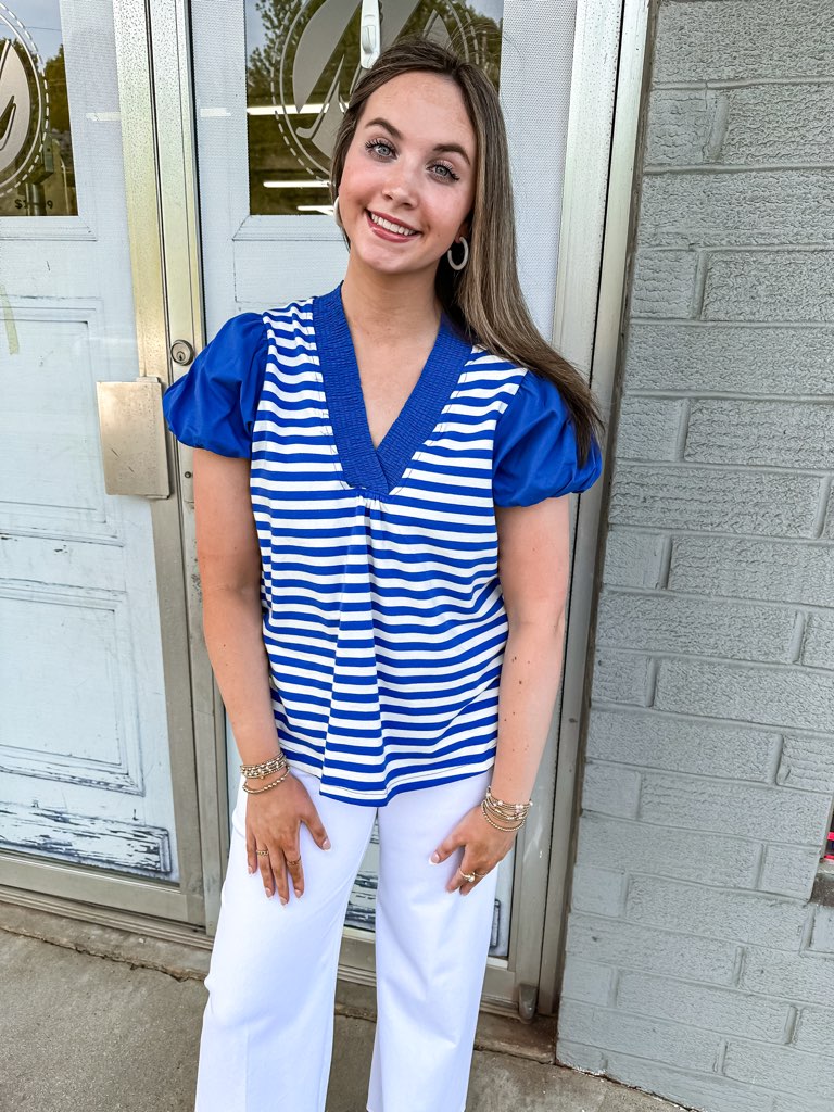 Laurell top with a smocked v-neckline and puff short sleeves in blue and white strips design. 