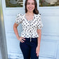 A black and white polka dot top with puff sleeves and an elastic waist and scoop neck design.