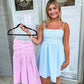 A short pink and white gingham print dress with a bow on the back. 