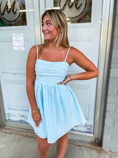 A short mint and white gingham print dress with a bow on the back. 
