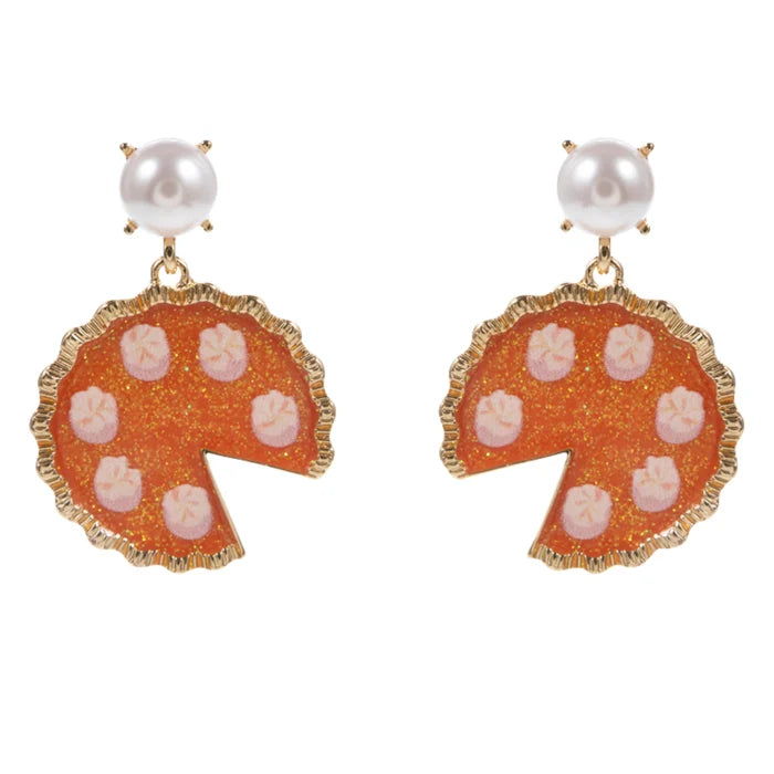A pair of gold-tone drop earrings featuring a scalloped orange enamel disc with pink starburst details, a white pearl at the top, and a small gold prong setting.