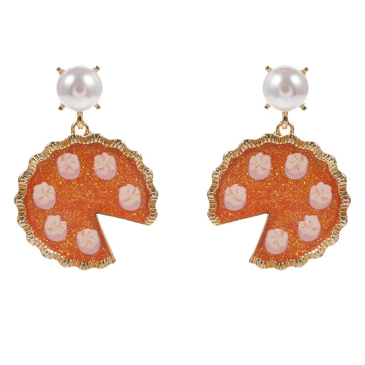 A pair of gold-tone drop earrings featuring a scalloped orange enamel disc with pink starburst details, a white pearl at the top, and a small gold prong setting.