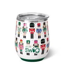 A Swig Christmas wine cup with a clear lid and a silicone seal around the edge. The body of the tumbler features colorful nutcrackers in various outfits. These nutcrackers are arranged in a grid-like pattern against a white background.