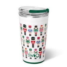 A Swig Christmas tumbler with a clear lid and a silicone seal around the edge. The body of the tumbler features colorful nutcrackers in various outfits. These nutcrackers are arranged in a grid-like pattern against a white background. 